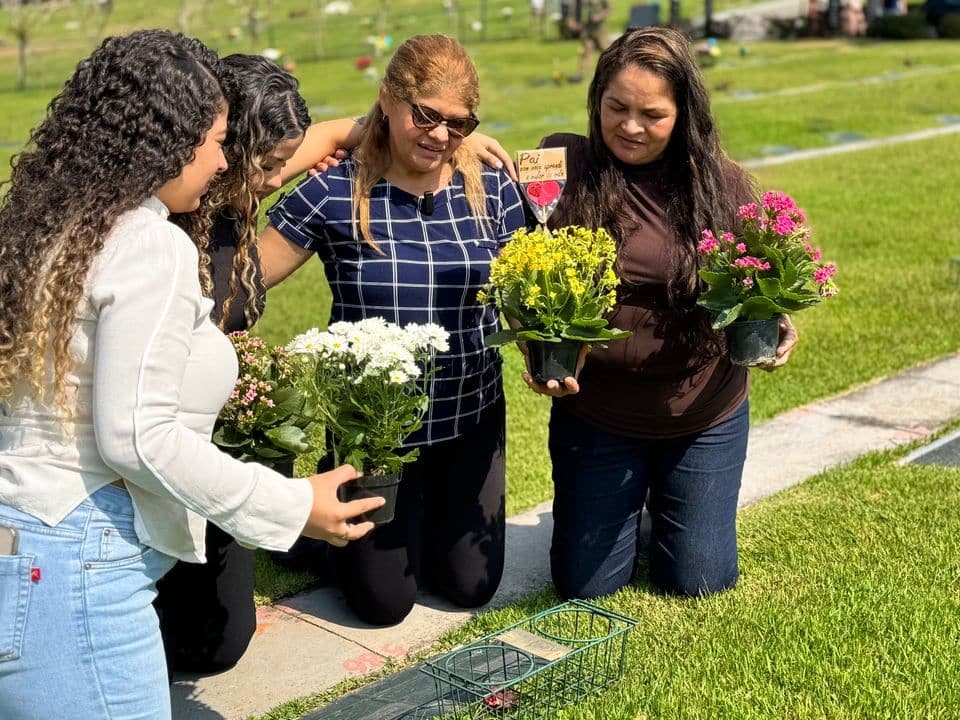 Família colocando flores em uma lápide no gramado do Valle dos Reis